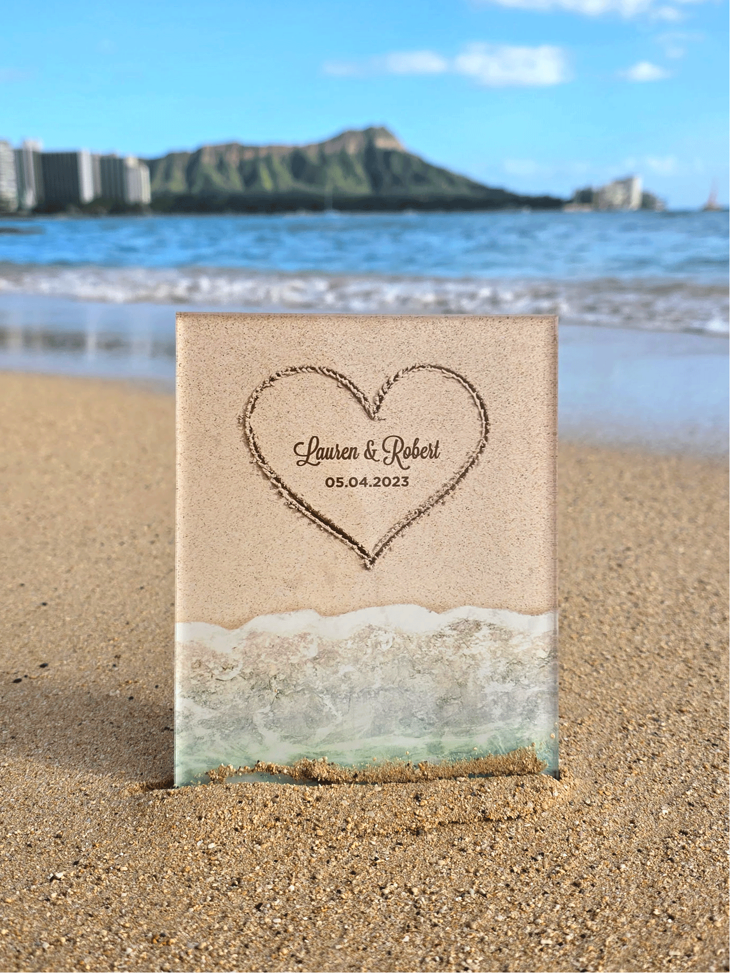 Heart-shaped engraving on a sand-like surface with ocean and skyline in the background