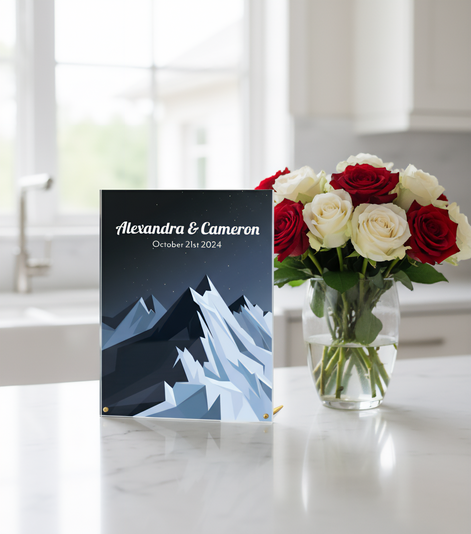 Personalized custom acrylic decor with mountain design next to a vase of red and white roses on a table.
